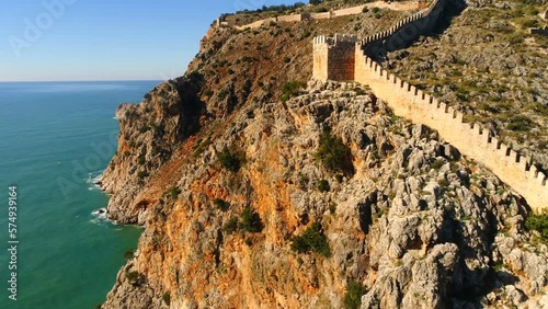 View of the beautiful Alanya fortress walls on the mountains overwashed by Mediterranean sea in sunny Antalya Province, Turkey. Flying copter back. photo