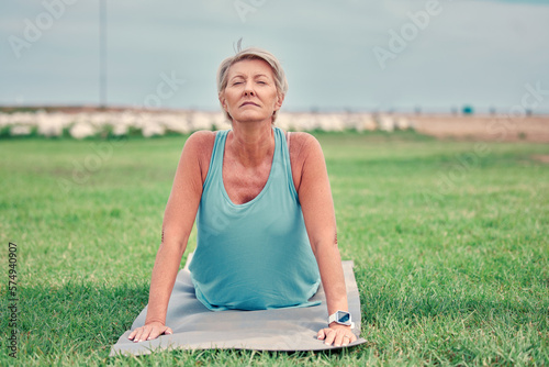 Cobra stretching, senior woman and exercise at park for workout, training and fitness. Elderly lady, yoga and flexible body outdoor on mat, grass and nature for wellness, healthy lifestyle or push up