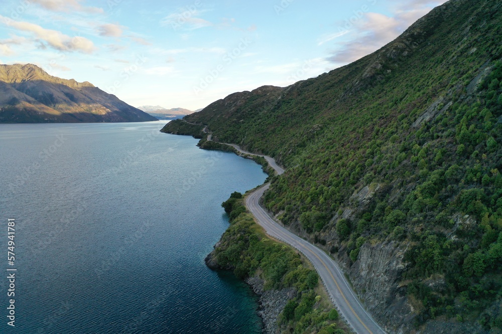 A road between a mountain and a lake