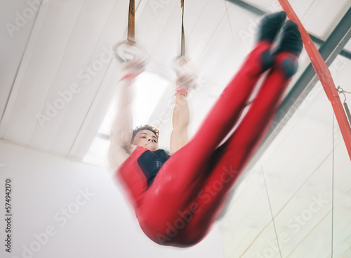Gymnastics, ring and sports with man in stadium and speed for fitness, workout or health challenge. Wellness, exercise and training with athlete lifting in gym arena for strong, power and motion blur