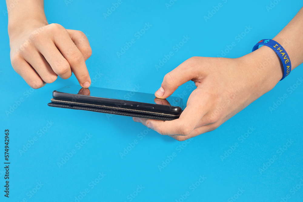 Autistic boy holding phone in two hands. Autism awareness. Autistic boy holding phone in two hands. Autism awareness.