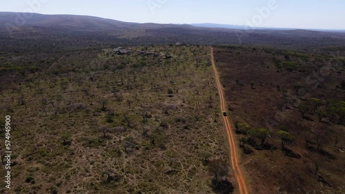 Ariel drone shot of a safari vehicle driving down a dirt road showing one fire-burnt area and an unburnt area in the winter months of Africa searching for wild animals photo