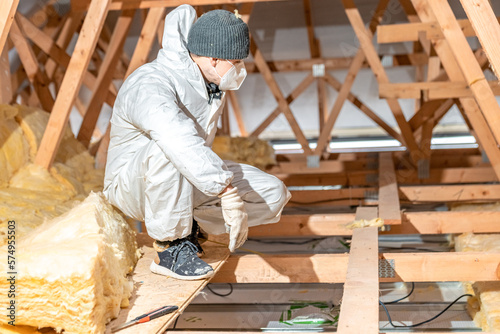 a worker in protective overalls works with glass wool