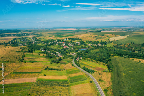 Fototapeta Naklejka Na Ścianę i Meble -  Air view of the countryside. Village, highway and cultivated fields on hills on a sunny summer day