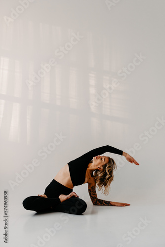 Woman with tattoos practicing Yoga and meditating with white background