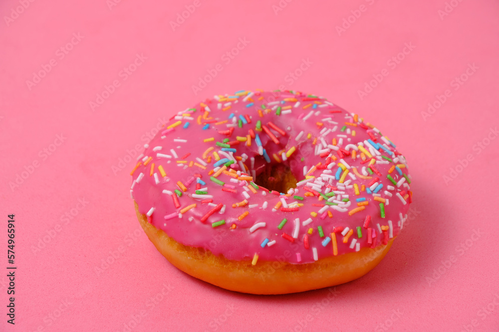 Donut with pink icing and multicolored sugar sprinkles.On pink background. Donut with pink icing and multicolored sugar sprinkles.On pink background.