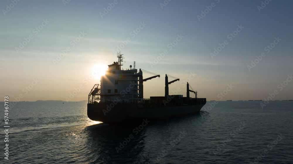 corgo ship container in silhouette and over the sunlight at evening in open sea. aerial view