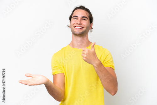 Caucasian handsome man isolated on white background holding copyspace imaginary on the palm to insert an ad and with thumbs up