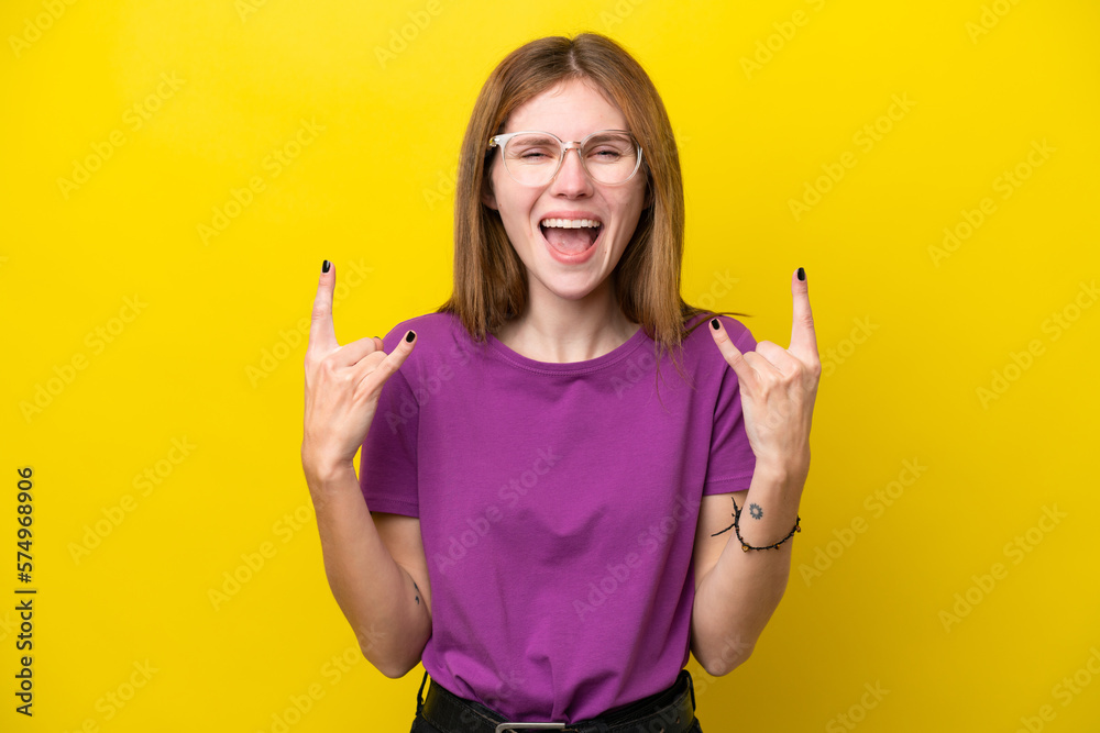 Young English woman isolated on yellow background making horn gesture Young English woman isolated on yellow background making horn gesture