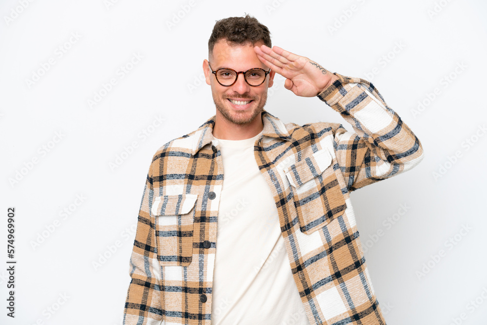 Young caucasian handsome man isolated on white background saluting with hand with happy expression