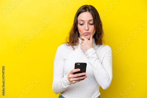 Young caucasian woman isolated on yellow background thinking and sending a message