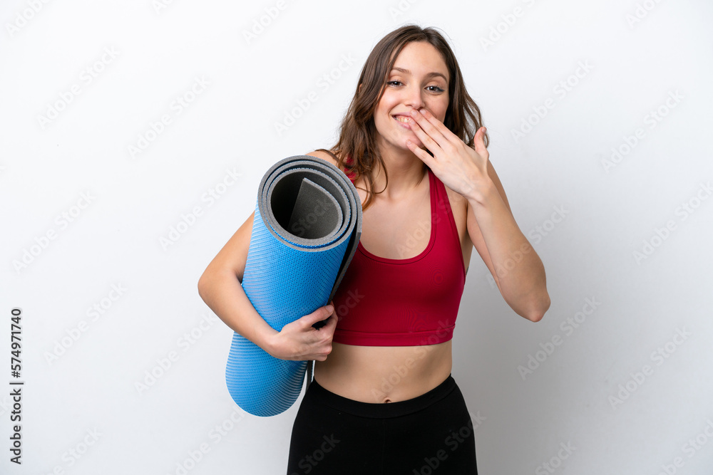 Young sport caucasian woman going to yoga classes while holding a mat isolated on white background happy and smiling covering mouth with hand Young sport caucasian woman going to yoga classes while holding a mat isolated on white background happy and smiling covering mouth with hand