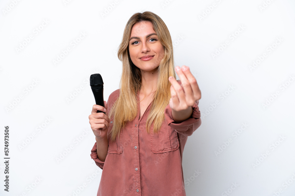 Singer Uruguayan woman picking up a microphone isolated on white background making money gesture Singer Uruguayan woman picking up a microphone isolated on white background making money gesture