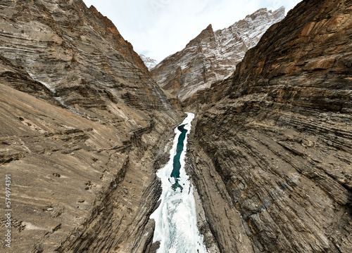 A frozen glass-like Zanskar river with dramatic Himalayan mountains on either side, in peak indian winter photo