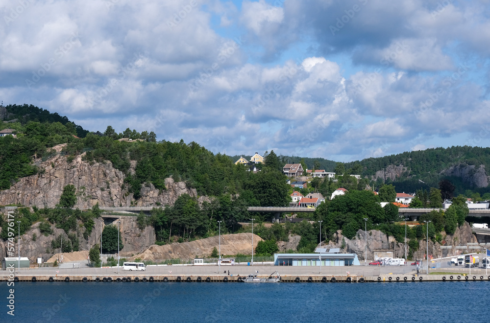 Blick vom Hafen von Kristiansand im südwestlichen Norwegen auf einen Teil der Häuser, Infrastruktur und umgebenen Natur der Stadt bei schönem Wetter, viel Copy Space