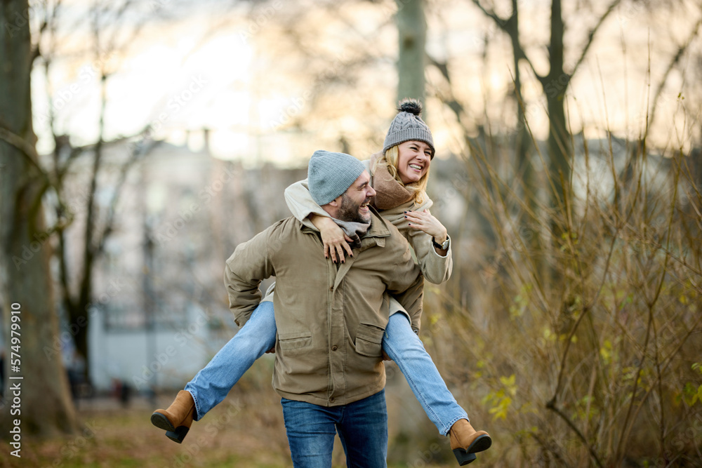 A handsome man giving his girlfriend a piggyback ride outdoors