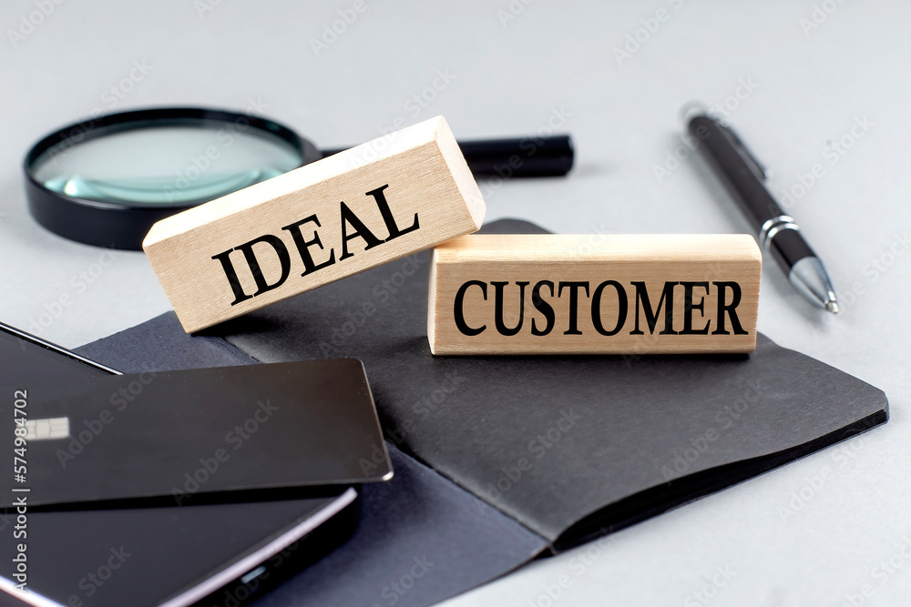 Fototapeta premium IDEAL CUSTOMER text on wooden block on black notebook , business concept