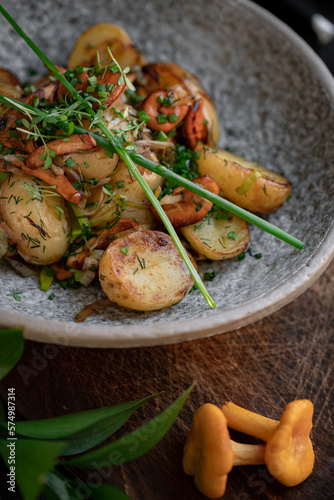 Fried potatoes with chanterelles and green onions in a gray bowl. Vegan dish with potatoes and mushrooms, selective focus, close up