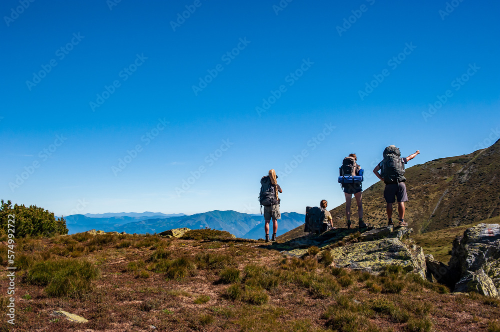 Group of trekkers hikers with backpacks looking at Maramures ridge from Rodna Mountains, Muntii Rodnei National Park, Romania, Romanian Carpathian Mountains, Europe.