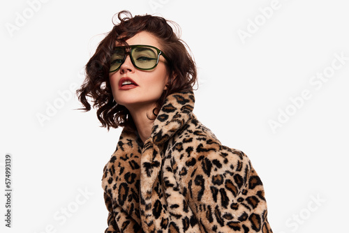 Half-length portrait of young beautiful expressive girl posing in stylish animal print furcoat isolated over white background. Concept of beauty, emotions, fashion