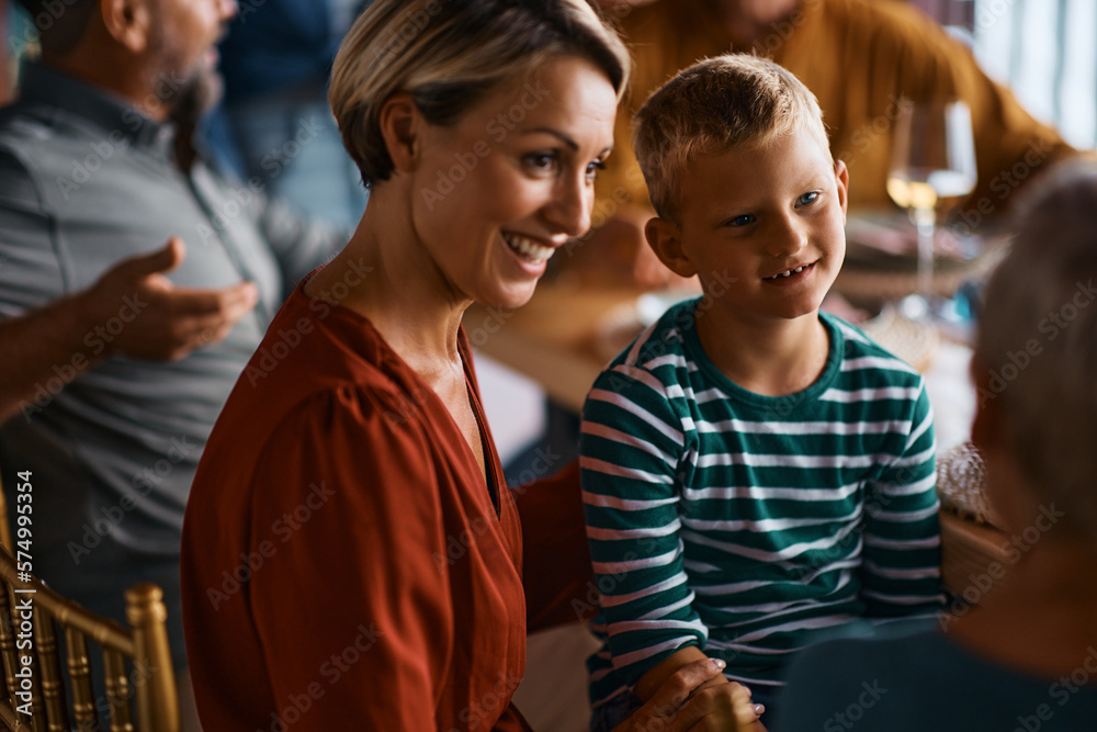 Obraz premium Happy boy talks to his mother and grandmother during family meal.