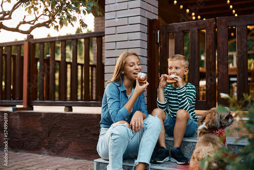 Photographie Teenage girl and her brother eat donuts in backyard.
