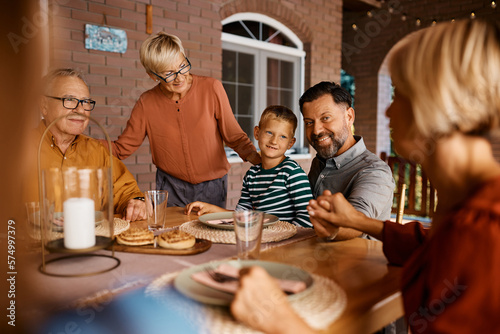 Happy multigeneration family talks while gathering for lunch on terrace.