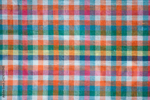 Colorful checkered tablecloth as background, top view.