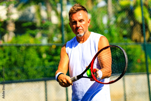 Senior tennis player playing tennis outdoors im sunny day