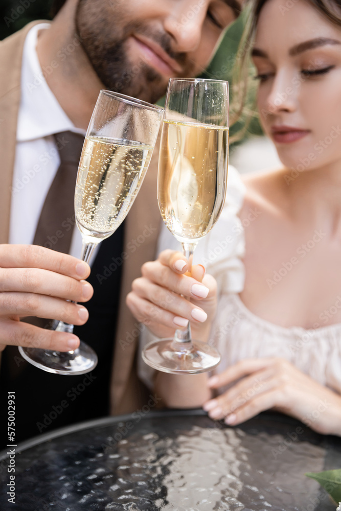 young newlyweds clinking glasses of champagne during wedding celebration.