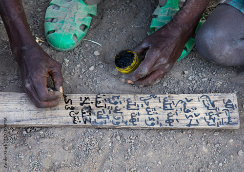 Afar tribe teacher writing on a wood board in a coranic school, Afar region, Afambo, Ethiopia photo