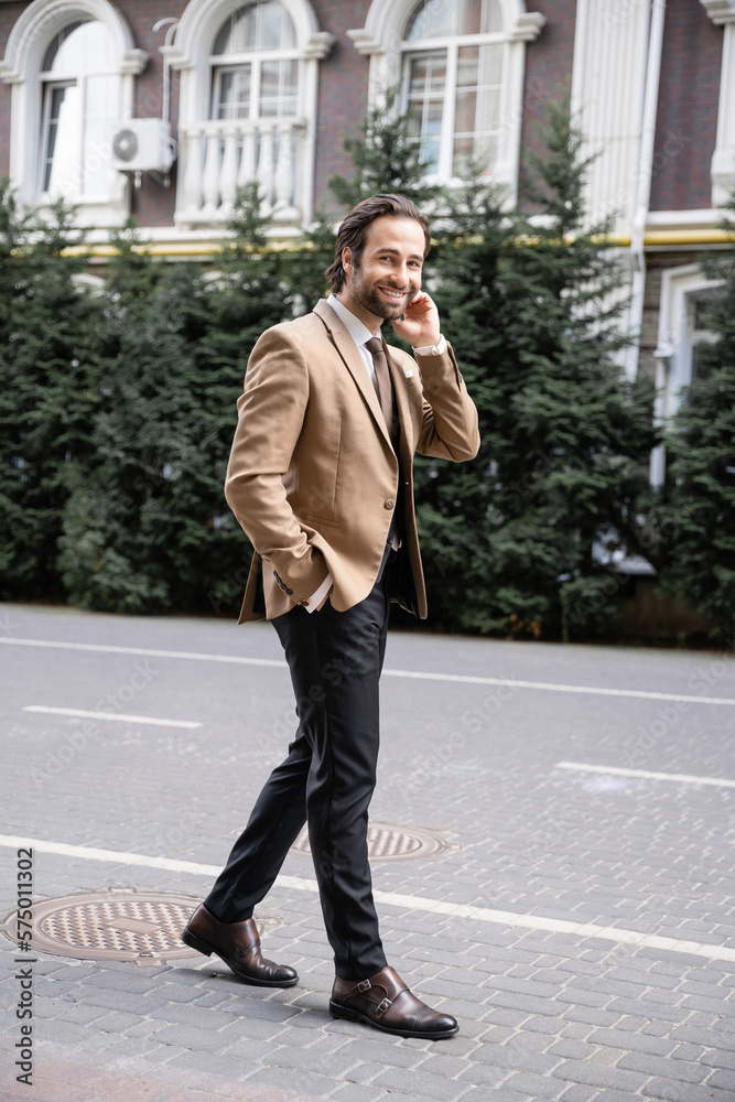 full length of cheerful man in beige formal wear standing with hand in pocket and looking at camera. full length of cheerful man in beige formal wear standing with hand in pocket and looking at camera.