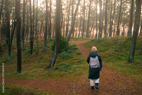 Photo from the back of woman discovering forest. Concept of traveling and outdoors wandering. © AlexGo