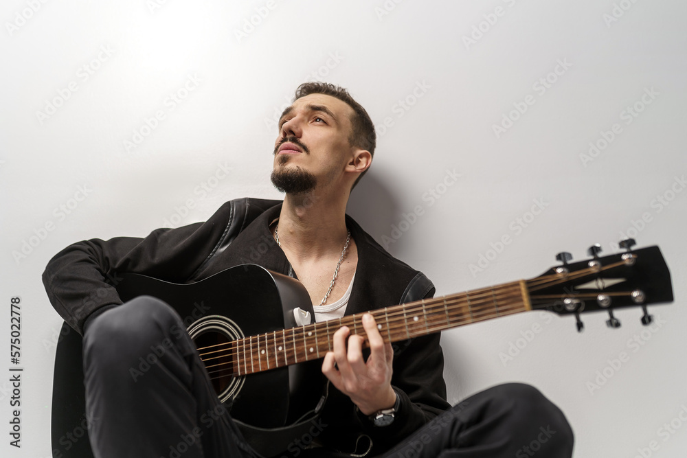 Young musician playing acoustic guitar and singing, on gray background Young musician playing acoustic guitar and singing, on gray background