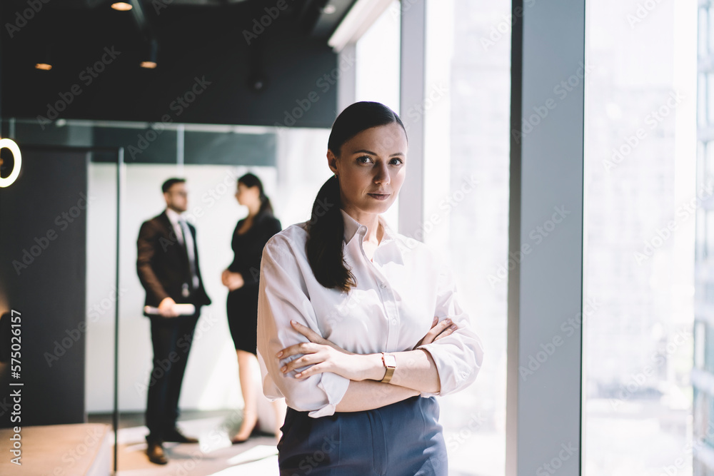 Confident businesswoman with crossed arms near colleagues Confident businesswoman with crossed arms near colleagues