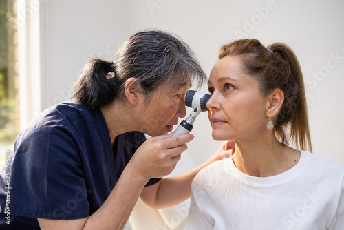 Female patient having her ears checked by a female nurse using an otoscope in the clinic photo