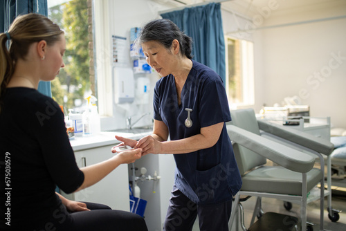 Health worker getting a blood sample from a woman using a blood lancet in the clinic photo