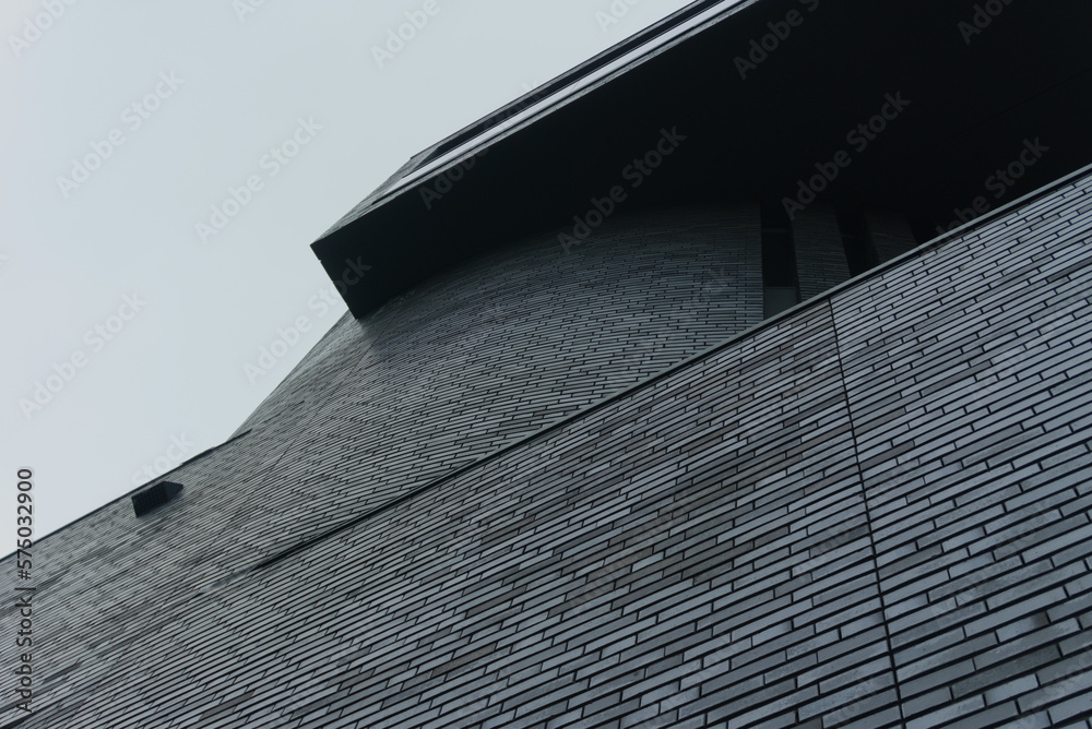 Naklejka premium nowoczesny budynek z ciemnej cegły na tle jasnego nieba