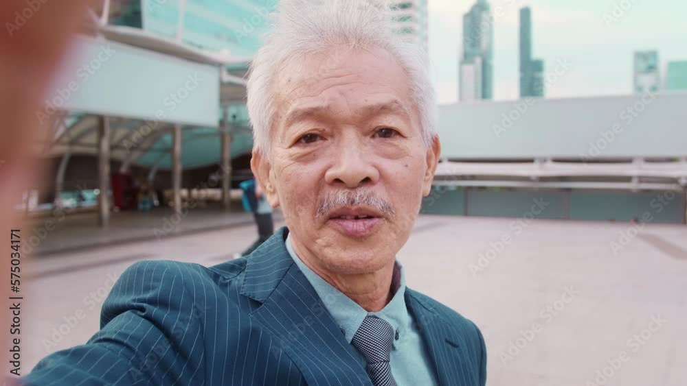 Asian senior mature middle aged businessman making video call in modern city Asian senior mature middle aged businessman making video call in modern city