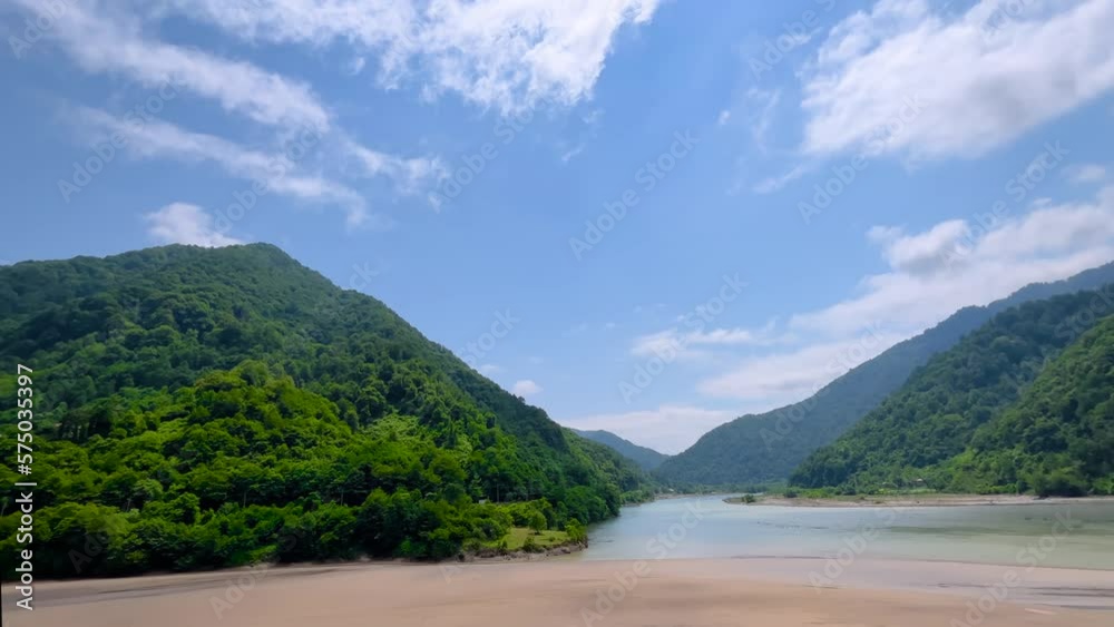 Panning shot: view of mountains with green trees, confluence of the two flowing rivers and blue cloudy sky in the afternoon - slow motion. Georgian landscape near Batumi in Georgia Panning shot: view of mountains with green trees, confluence of the two flowing rivers and blue cloudy sky in the afternoon - slow motion. Georgian landscape near Batumi in Georgia