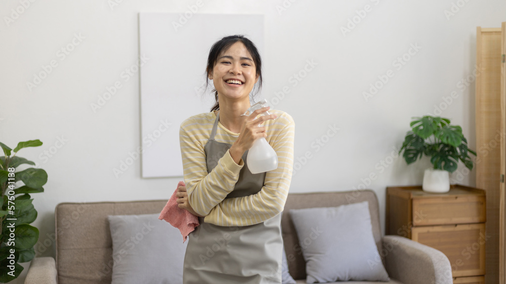 Asian housewife wearing apron holding rag and cleaning spray prepares for a big cleanup in the house, Housework, Daily routine, Big cleaning, Deep stain remover, Clean up on weekends. Asian housewife wearing apron holding rag and cleaning spray prepares for a big cleanup in the house, Housework, Daily routine, Big cleaning, Deep stain remover, Clean up on weekends.