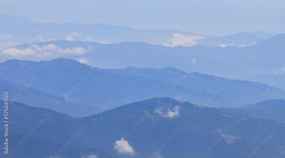 Obraz premium mountain chain silhouette in blue mist, natural mountain travel background