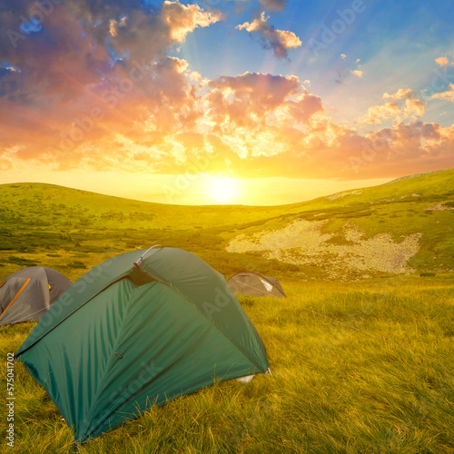 touristic tent among green hills at the sunset, mountain travel scene