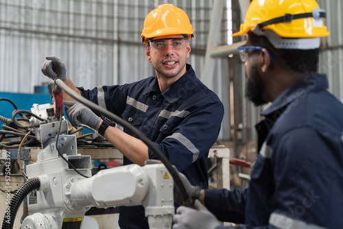 Group of male engineer workers discuss and working, checking, repair, maintenance automatic welding robot arm machine at production line in the industry factory © amorn