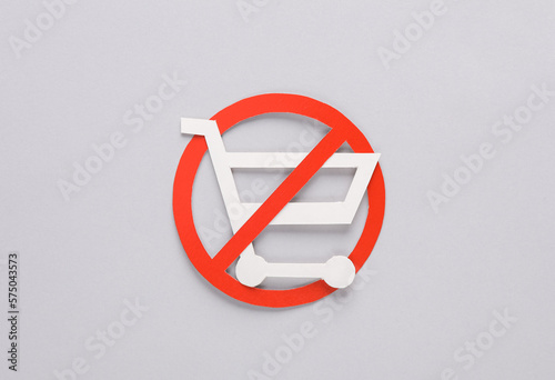 Paper cut shopping cart with prohibition sign on gray background
