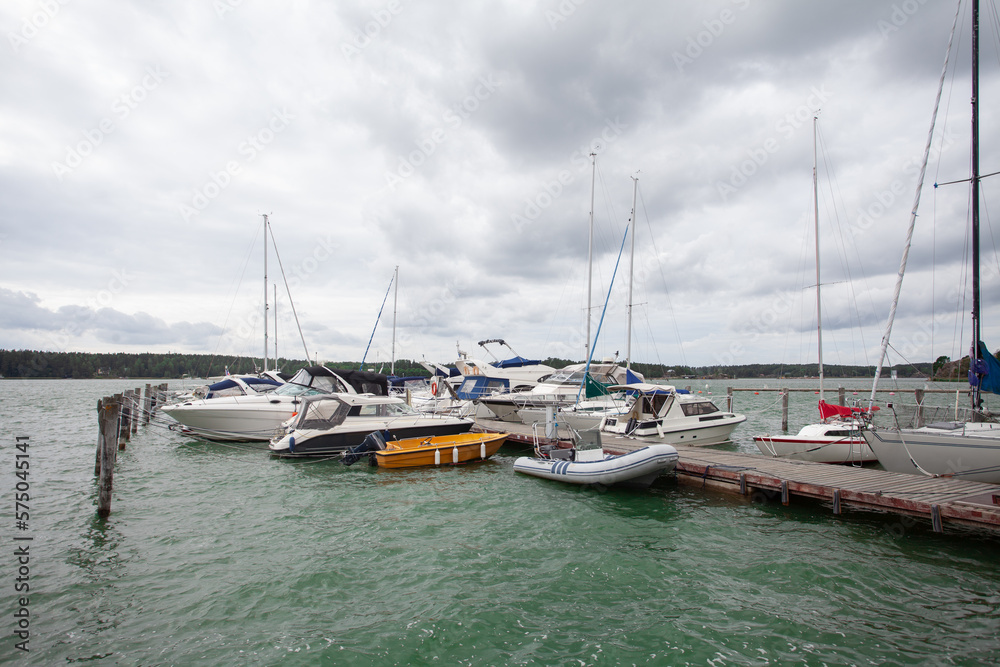 Yachts and boats on wooden pier on the background of cloudy sky