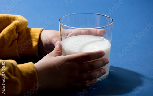 glass glass with milk in the hands of little child, yellow and blue colors, ucrania colors