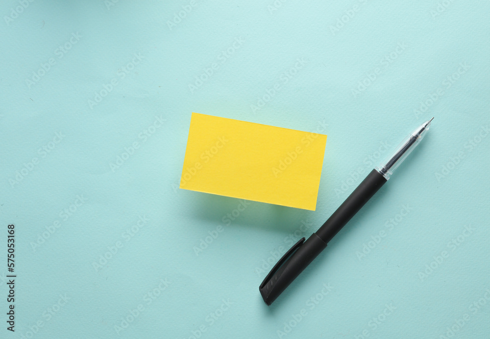 Yellow business card with a pen on a blue background. Top view Yellow business card with a pen on a blue background. Top view