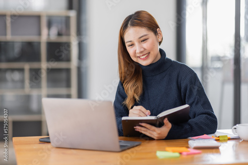 Asian Business woman using calculator and laptop for doing math finance on an office desk, tax, report, accounting, statistics, and analytical research concept 