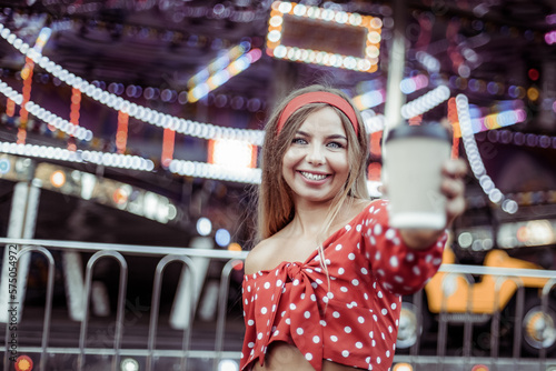 Portrait of cute smiling woman with coffee on the go in amusement park